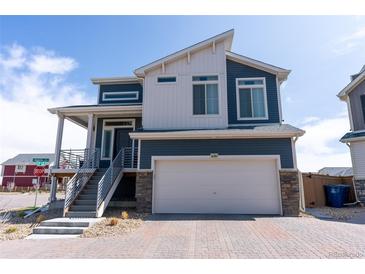 Charming two-story home with a blue and white facade, and a two-car garage with a brick driveway at 16382 E 111Th Dr, Commerce City, CO 80022