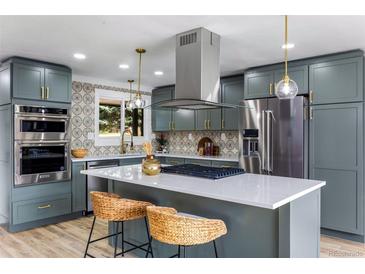 Modern kitchen with stainless steel appliances, island with cooktop, gray cabinets, and designer backsplash at 7120 S Sheridan Ct, Littleton, CO 80128