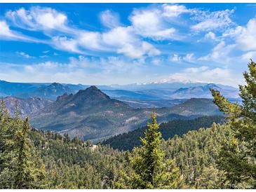 Expansive mountain vista with snow-capped peaks and evergreen forests under a blue sky with scattered clouds at 13288 Elsie Rd, Conifer, CO 80433