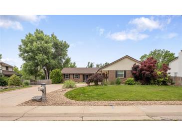 Charming ranch home with a well-manicured lawn, mature trees, and a neatly paved driveway at 5292 W Fair Dr, Littleton, CO 80123