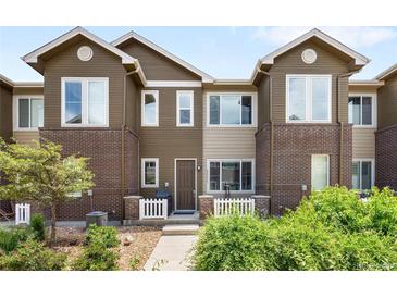 Attractive two-story townhome with brick accents, white picket fence, and manicured landscaping at 15546 W 64Th Loop # C, Arvada, CO 80007