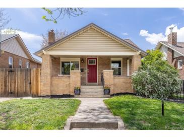 Charming brick bungalow featuring a classic front porch, red door, and well-manicured lawn at 3649 N Garfield St, Denver, CO 80205