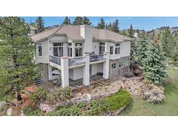 Stunning home with a patio, stone accents, lush landscaping, and a private balcony to take in the wooded views at 730 Summerwood Dr, Golden, CO 80401