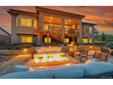 Inviting outdoor patio with a cozy fire pit and ample seating for relaxation and entertaining under a covered deck at 5388 Water Oak Cir, Castle Rock, CO 80108