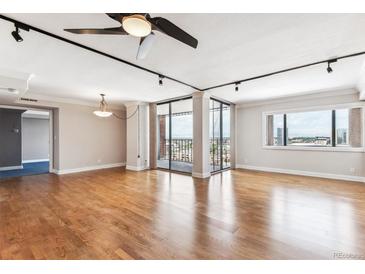 Bright living room features hardwood floors, ceiling fan, and sliding glass doors to a balcony with city views at 1551 Larimer St # 1803, Denver, CO 80202