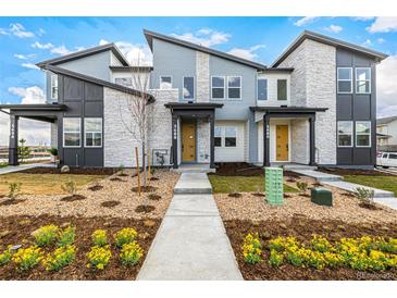 Modern townhome with stone accents, tidy landscaping, a walkway and a sunny yellow front door at 5688 N Killarney Ct, Aurora, CO 80019