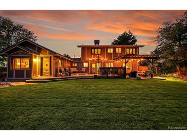 A spacious backyard features a pergola, outdoor seating, and a large lawn for relaxation and entertainment at 7678 Newman St, Arvada, CO 80005