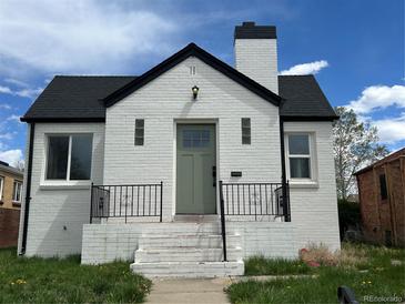 Charming white brick home with a black roof, a lovely green door, and decorative wrought iron railings at 3532 N Fillmore St, Denver, CO 80205