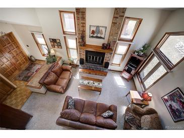 Bright living room featuring a brick fireplace and multiple windows for natural light at 283 Yank Ct, Lakewood, CO 80228
