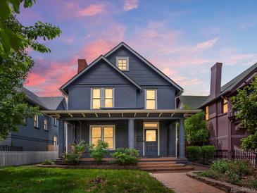 Charming two-story home with a welcoming front porch and manicured lawn, showcasing classic architectural details at 1423 Elizabeth St, Denver, CO 80206