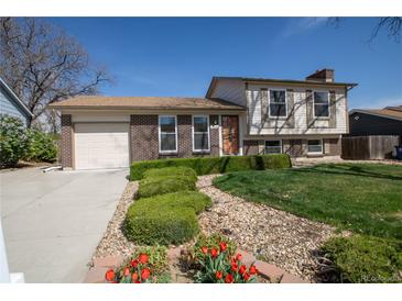 Charming brick and siding two-story home with a well-manicured lawn, flower bed, and attached garage at 1838 Cedar St, Broomfield, CO 80020
