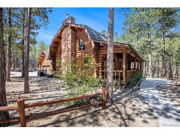 Charming log home with brick chimney and covered porch nestled among trees at 17940 Smugglers Rd, Monument, CO 80132