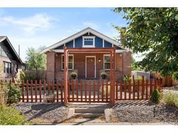 Charming brick home with a picket fence and a welcoming covered porch entrance at 1534 Meade St, Denver, CO 80204