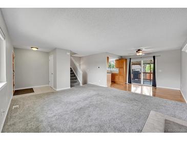 Open-concept living room boasts neutral colors, soft carpet, and sliding glass doors to the deck at 8595 Field Ct, Arvada, CO 80005
