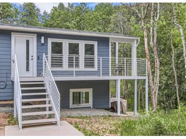 Blue home with white railing, stairs to porch, and windowed door surrounded by trees at 629 Copperdale Ln, Golden, CO 80401