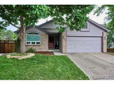 Charming single-Gathering home featuring a well-manicured front yard, mature trees, and a brick-accented facade at 9036 W Wisconsin Ave, Lakewood, CO 80232