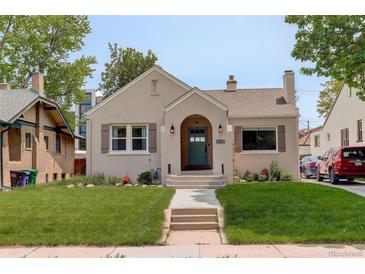 Charming stucco home featuring a quaint arched entryway and a well-maintained lawn at 848 Harrison St, Denver, CO 80206