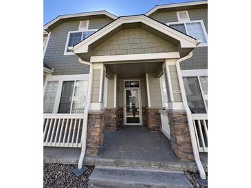 Inviting front porch with stone accents and white railings offers a warm welcome to this charming home at 15955 E Geddes Dr # 55, Aurora, CO 80016