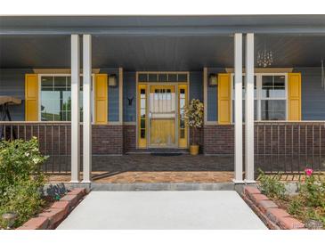 Inviting front entrance with a decorative yellow door and brick accents leading to a cozy porch at 3967 Eastout Ave, Parker, CO 80138