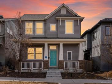 Charming two-story home with a welcoming front porch and a bright blue front door at 10000 E 59Th Dr, Denver, CO 80238