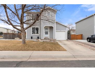 Charming gray two-story home featuring a well-manicured front yard, attached garage, and inviting entryway at 1212 Magpie Ave, Brighton, CO 80601