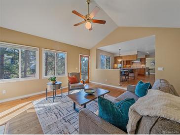 Bright living room featuring hardwood floors, modern furniture, ceiling fan, and natural light at 4228 Scenic Village Dr, Evergreen, CO 80439