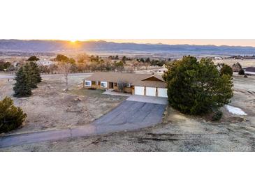 Ranch-style home with three-car garage, set against a mountain backdrop at sunset at 10353 N Chatfield Dr, Littleton, CO 80125