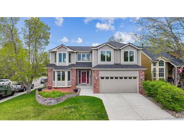 Charming two-story home featuring a well-manicured lawn and a two-car garage with red brick and a red door at 5282 Devon Ave, Castle Rock, CO 80104