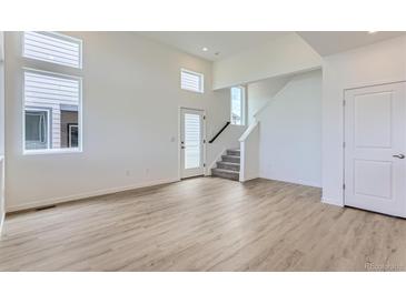 Bright living room boasts large windows, wood-look floors, and access to the staircase at 1284 S Algonquian St, Aurora, CO 80018