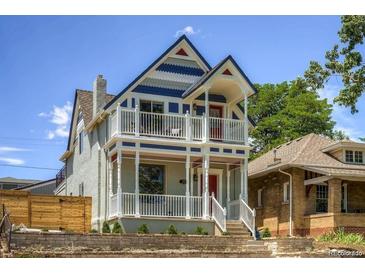 Charming two-story home featuring a double-decker porch, a red front door, and stone wall landscaping at 2021 Eliot St, Denver, CO 80211