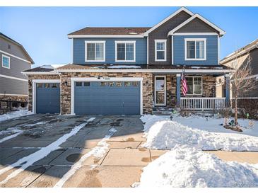 Two-story house with blue siding, two-car garage, and snowy front yard at 7097 S Patsburg Way, Aurora, CO 80016