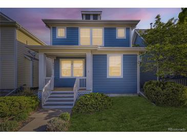 Charming two-story home with a blue exterior, inviting front porch, and well-maintained lawn at 4689 Tanner Peak Trl, Brighton, CO 80601