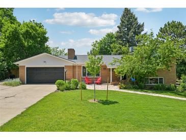 Charming brick home with a well-manicured lawn, lush landscaping, and inviting front porch with red chairs at 721 Park Ln, Lakewood, CO 80214