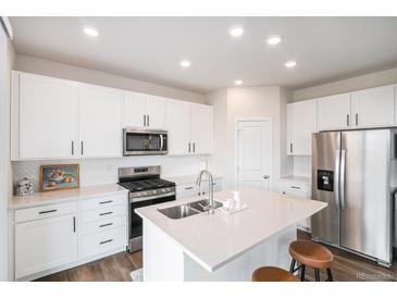 Bright kitchen features white cabinets, stainless steel appliances, and an island with a sink at 5805 Red Barn Ave, Longmont, CO 80504