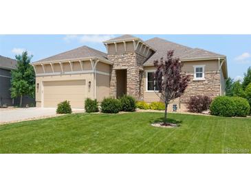 Charming one-story home with a manicured lawn, stone accents, and a two-car garage at 15779 W 83Rd Pl, Arvada, CO 80007