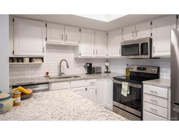 Well-lit kitchen featuring white cabinets, subway tile backsplash, and stainless steel appliances at 14091 E Marina Dr # 612, Aurora, CO 80014