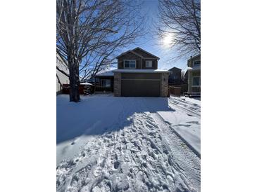Charming two-story home featuring a two-car garage, a welcoming front porch, and a snow-covered yard at 3610 Morning Glory Dr, Castle Rock, CO 80109