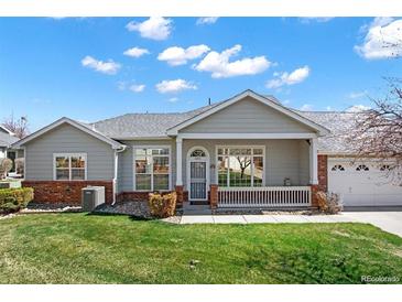 Inviting single-story home featuring a charming front porch and a well-manicured lawn at 3231 E 102Nd Pl, Thornton, CO 80229