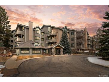 Inviting exterior of a multi-story condo building with stone accents and manicured landscaping against a colorful sunset at 31719 Rocky Village Dr # 317, Evergreen, CO 80439