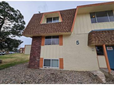 Multi-Gathering townhouse exterior with brown shingled roof, tan siding, brick, and rocks at 10211 Ura Ln # 5-206, Thornton, CO 80260