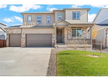 Charming home featuring a front porch, stone accents, well-maintained lawn, and a two-car garage at 13489 Valentia Pl, Thornton, CO 80602