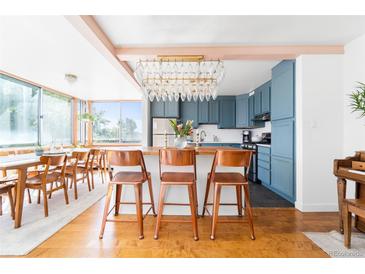Bright kitchen featuring blue cabinets, wood countertops, a chandelier, and seating at the kitchen island at 800 Washington St # 302, Denver, CO 80203
