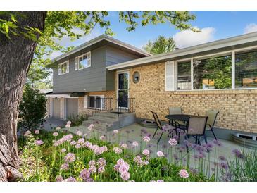 Charming home with a brick facade, complemented by lush landscaping and a cozy outdoor seating area at 1713 S Holland St, Lakewood, CO 80232
