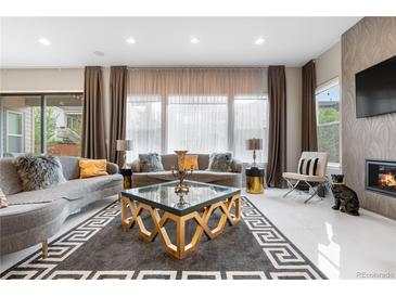 A stylish living room featuring couches, a fireplace, a glass coffee table and bright windows with decor at 11193 Mission Walk St, Parker, CO 80134