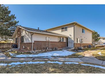 Two-story home featuring a brick foundation and light siding under a blue sky at 3354 S Flower St # 14, Lakewood, CO 80227