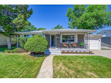 Charming brick home featuring a well-manicured lawn, inviting front porch with chairs, and tidy landscaping at 7011 Poplar St, Commerce City, CO 80022