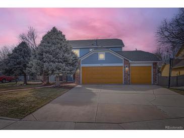 Two-story home with a two-car garage, mature trees, and a well-maintained lawn under a colorful pink and purple sky at 4027 Hawthorne Cir, Longmont, CO 80503