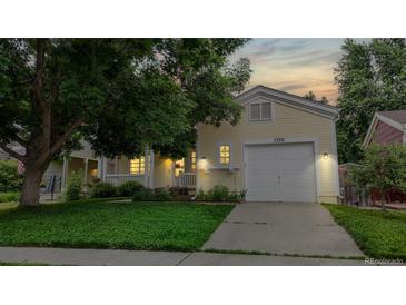 Charming yellow home featuring an attached garage and well-maintained lawn at 1750 Clark Dr, Erie, CO 80516