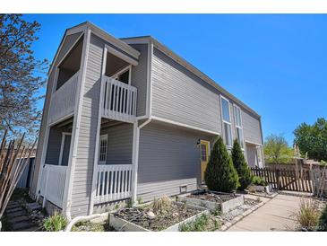 Stylish two-story home with dual balconies, gray siding, garden boxes, and a bright yellow door at 1403 Valentia St, Denver, CO 80220