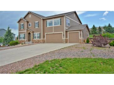 View of a multi-story house with a three-car garage and a well-maintained driveway with decorative rock at 735 Woodmoor Acres Dr, Monument, CO 80132